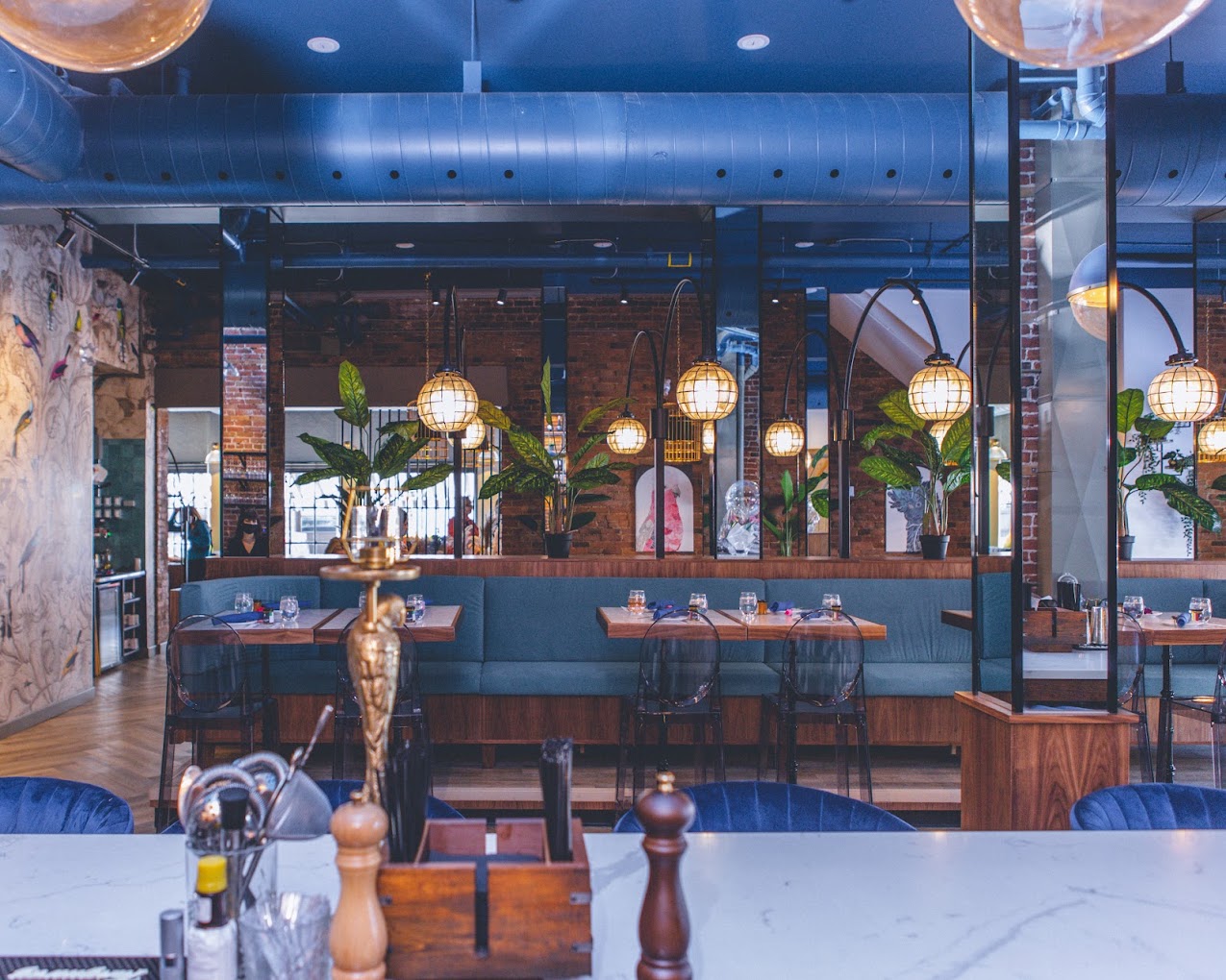Inside Starling Restaurant and Apothecary Lounge: deep blue ceilings, exposed brick, warm globe lighting and set tables