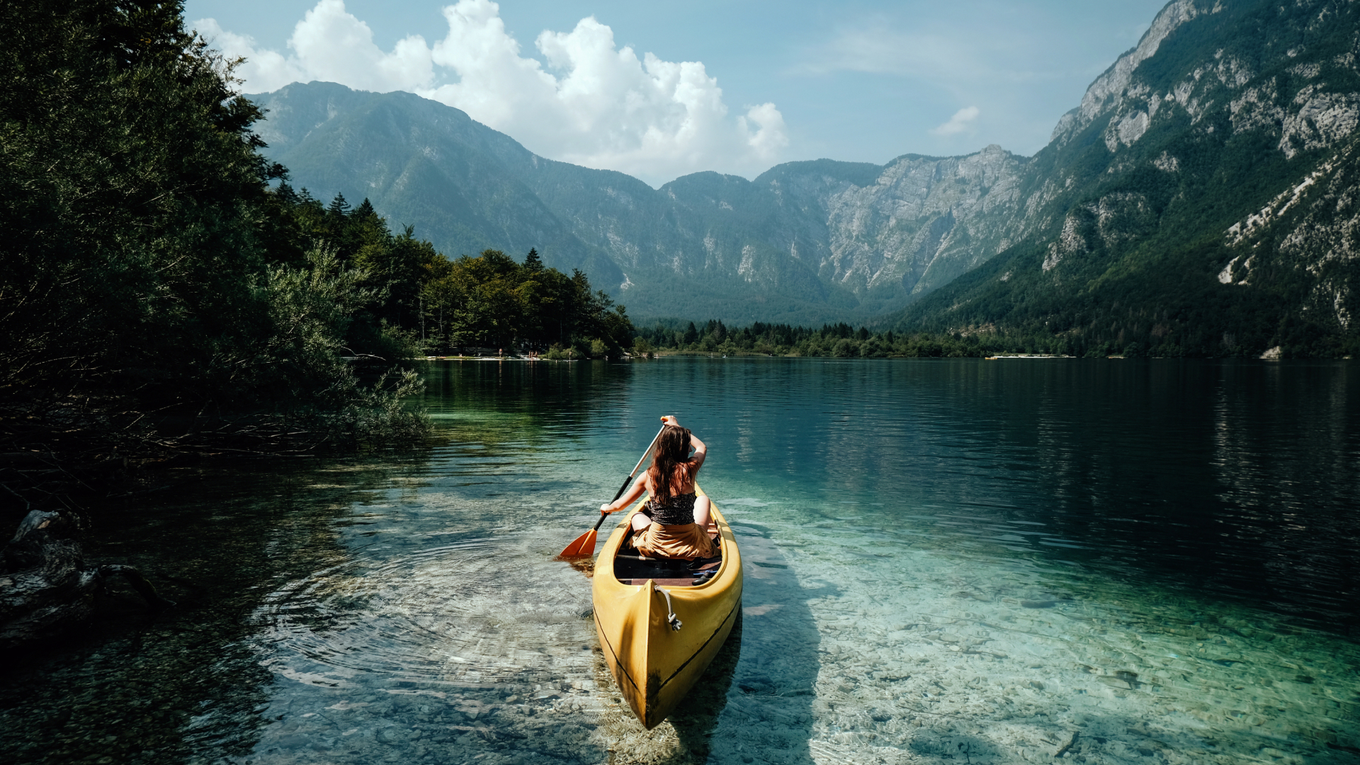 Traveller paddling a canoe across a clear mountain lake in Canada