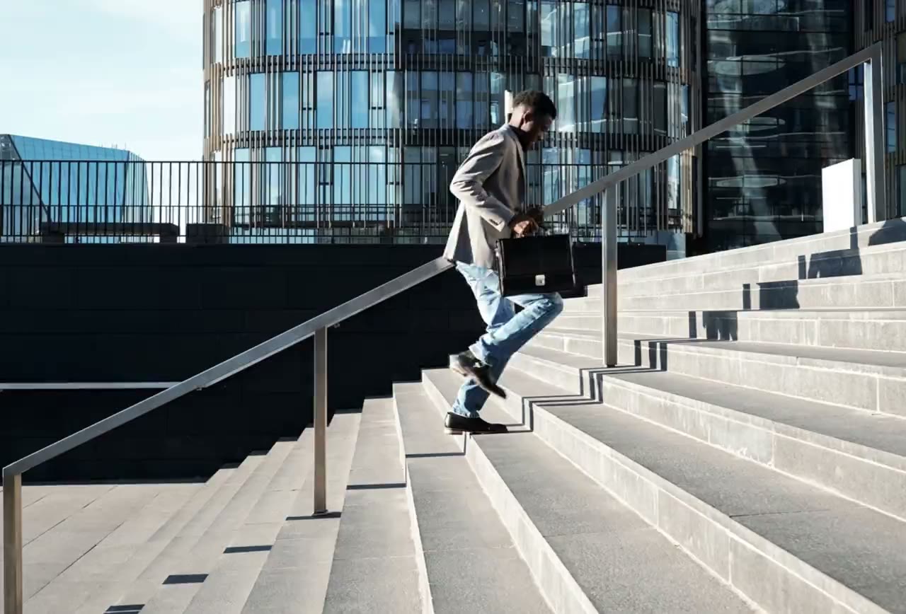Professional walking up steps toward a modern office tower
